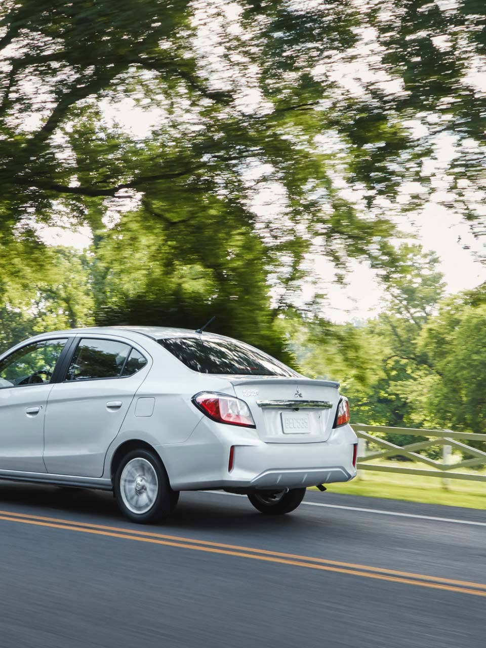 Angled back view of a white 2024 Mitsubishi Mirage G4 Sedan driving