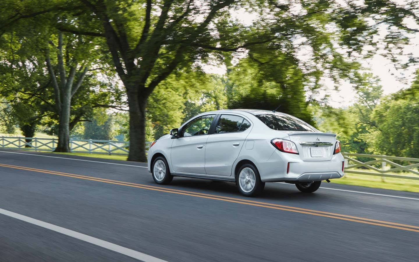 Angled back view of a white 2024 Mitsubishi Mirage G4 Sedan driving