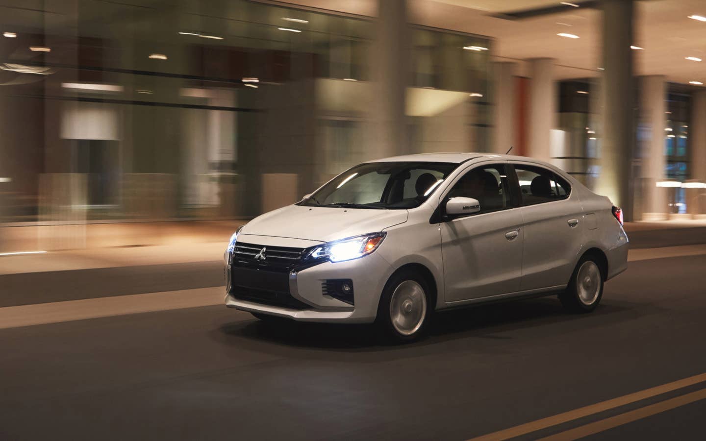A white 2024 Mitsubishi Mirage G4 Sedan driving fast through the city