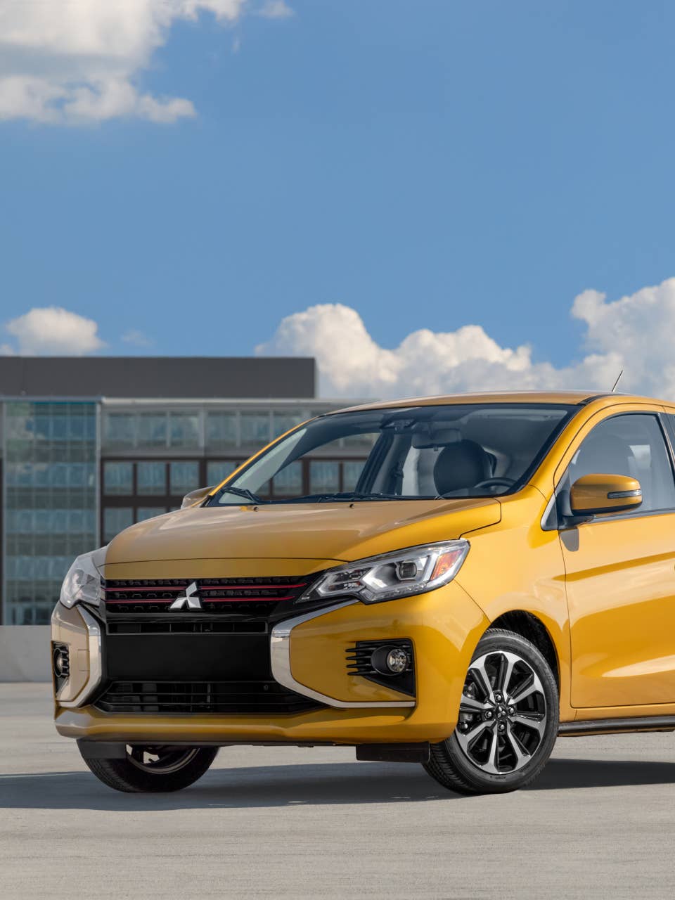 Yellow 2024 Mitsubishi Mirage Compact Hatchback parked in front of some buildings