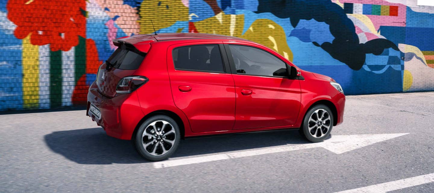 A red 2024 Mitsubishi Mirage Compact Hatchback parked in front of a colorful mural