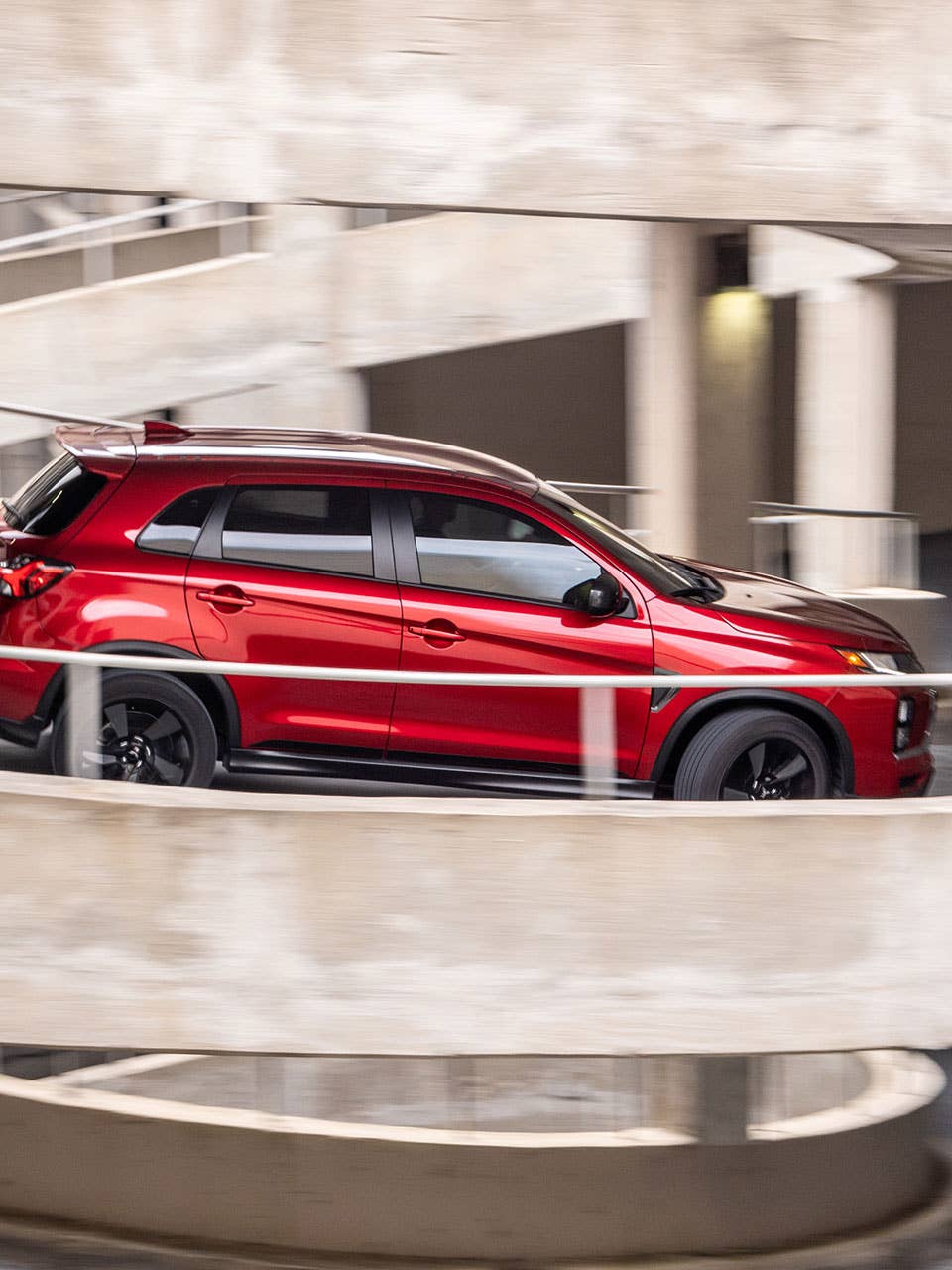 A red 2024 Mitsubishi Outlander Sport SUV driving down a ramp