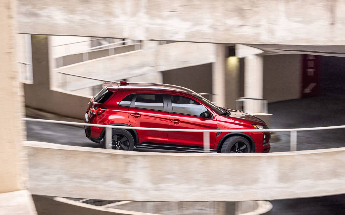 A red 2024 Mitsubishi Outlander Sport SUV driving down a ramp