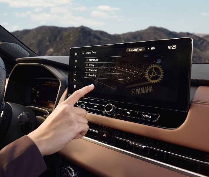 Mano interactuando con la pantalla de la Mitsubishi Outlander 2026, destacando el sistema de sonido dinámico Yamaha.