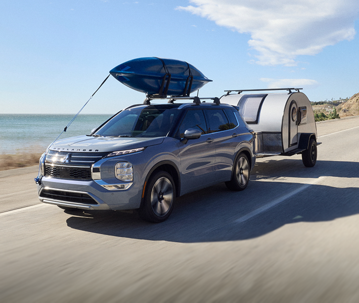 2026 Mitsubishi Outlander SUV towing a trailer to show off the vehicle's towing capacity. 