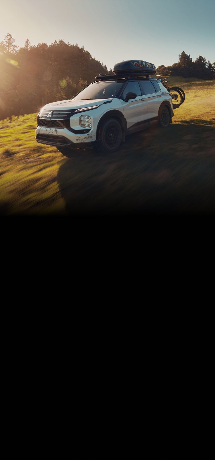 A white 2025 Mitsubishi Outlander Trail Edition SUV driving